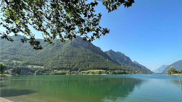 Ein ruhiger See mit Bergen im Hintergrund und einem klaren Himmel.