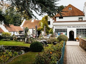 Situated in a serene garden, the Fondation Paul Delvaux Museum features a beautiful red-tiled roof and outdoor seating areas.