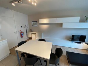 Cozy retreat with a dining table for four, flat-screen TV, and a potted plant.