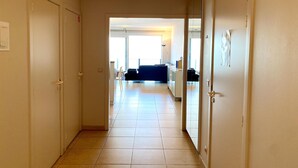Un pasillo con puertas que dan a una sala de estar con un sofá y una mesa de comedor.