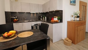 A modern kitchen with a central island, black chairs, and a dining table with fruit.