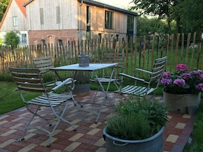 An outdoor patio with a table and chairs, surrounded by a wooden fence and a brick wall. - Holiday Apartment Sternhoh (Steinberg)