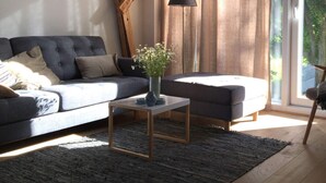 A modern living room with a dark sofa, a small side table, and a lamp.