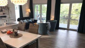 Una sala de estar moderna con comedor, ventanas amplias y un balcón.