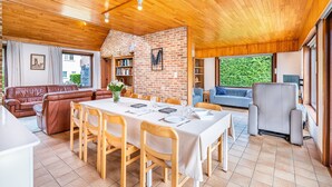 A cozy interior with a dining area, a sofa, a bookshelf, and a window with a view of greenery. - Villa in St-idesbald Near Sea Beach (Koksijde)