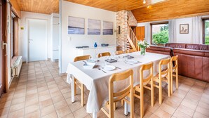 A dining area with a wooden table set for six, a brick fireplace, and a view of the outdoors through a window. - Villa in St-idesbald Near Sea Beach (Koksijde)