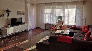 Un soggiorno moderno con televisione a schermo piatto, un divano, una poltrona a dondolo e un tavolino da caffè.