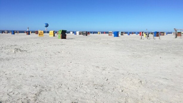 Una spiaggia sabbiosa con colorate casette sulla spiaggia e un cielo azzurro limpido.