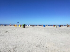 Ein Sandstrand mit bunten Strandkörben und einem strahlend blauen Himmel.