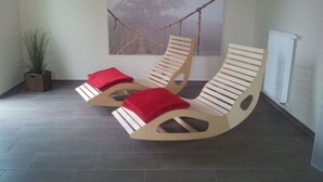 Two wooden lounge chairs with red cushions, a potted plant, and a wall-mounted hammock. - Residence on Lake Balmer (Benz)