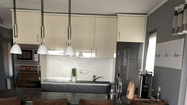 Cozinha moderna com ilha central, banquetas e máquina de café.