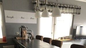 Cozinha moderna com uma ilha grande, iluminação pendente e uma backsplash com uma frase.