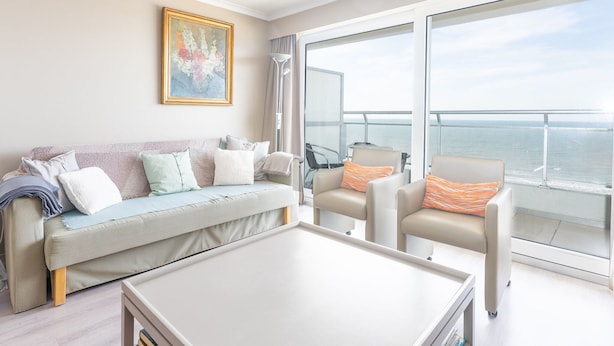 A modern living room with a sofa, two armchairs, a coffee table, and a large window offering a view of the sea. - Apartment on the 9th Floor With sea View (Middelkerke)