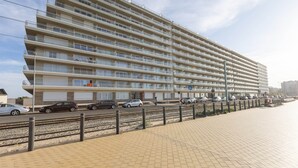 A multi-story hotel with balconies, located near a beach with a paved walkway and parked cars. - Apartment on the 9th Floor With sea View (Middelkerke)