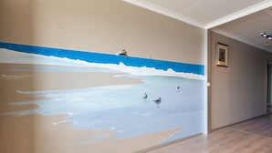 A hallway with a wall mural of a beach scene, a framed picture on the wall, and wooden flooring. - Apartment on the 9th Floor With sea View (Middelkerke)