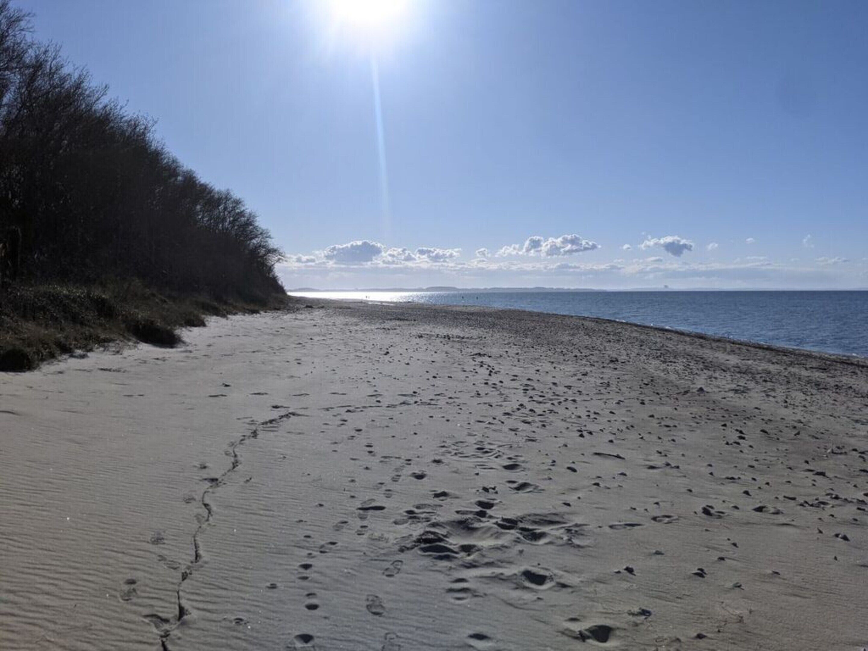 Une plage de sable avec des empreintes et un ciel dégagé.