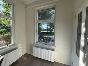 Una habitación con un ventanal grande, un radiador y vistas a un jardín.