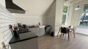 A modern kitchen with white subway tiles, a black countertop, and a dining area with a table and chairs.