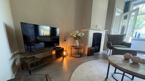 A living room with a flat-screen TV, a fireplace, a sofa, and a round coffee table.