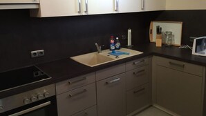 A modern kitchen with white cabinets, a black countertop, a sink, and a stove. - Holiday Apartment Wurzburg (Würzburg)