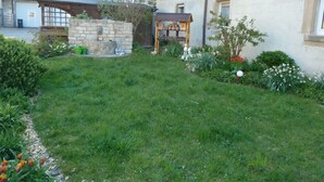 A garden with a stone structure, a wooden bench, and various plants. - Nice Apartment in Himmelkron (Himmelkron)