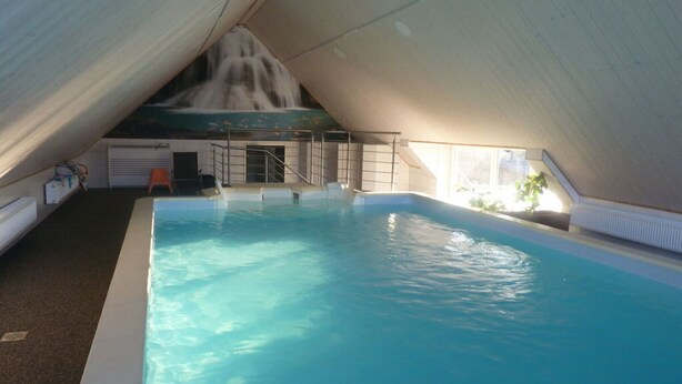 An indoor swimming pool with a sloped ceiling and a view of a waterfall. - Nice Apartment in Himmelkron (Himmelkron)