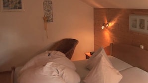 A bedroom with a bed, pillows, a wooden headboard, a wall-mounted light fixture, and a framed picture. - Holiday Apartment Waxenstein (Lenggries)