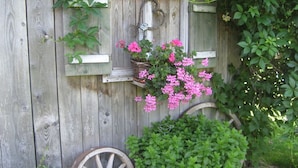 A rustic wooden structure with a hanging flower basket and a wheel. - Holiday Apartment Waxenstein (Lenggries)