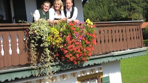 A balcony with a wooden railing and a flower box filled with various flowers. - Holiday Apartment Waxenstein (Lenggries)