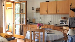 A cozy kitchen with wooden cabinets, a dining table with chairs, and a small dining area with a sofa. - Holiday Apartment Waxenstein (Lenggries)