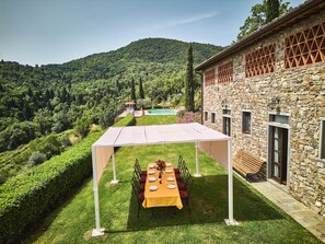 A stone building with a covered outdoor dining area, a pool, and a lush green landscape. - Tranquil Chianti Escape for 4 (Cavriglia)