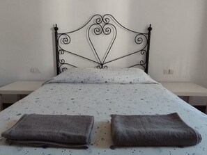 A bed with a metal headboard, two bedside tables, and a bedspread with a star pattern. - Belvilla by OYO Cortijos del Sol (Alhaurin de la Torre)