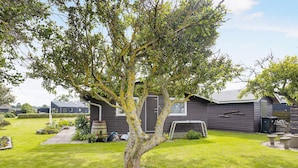 A residential property with a well-maintained lawn, a tree, and a house with a dark exterior. - 5 Person Holiday Home in Saeby (Sæby)