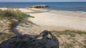 A beach with a rocky outcrop, sandy shore, and sparse grass. - 5 Person Holiday Home in Saeby (Sæby)