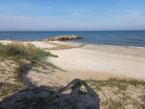 A beach with a rocky outcrop, sandy shore, and sparse grass. - 5 Person Holiday Home in Saeby (Sæby)