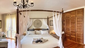 A four-poster canopy bed with a wooden headboard, a round wall decoration, and a large wooden wardrobe. - Quinta Martin Modern Retreat (Funchal)