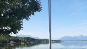 A lakeside view with a metal railing, clear water, and distant mountains.