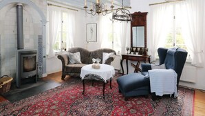 A cozy room with a fireplace, a chandelier, and a large mirror. - Swanenhuus Modern Retreat (Krummhoern)