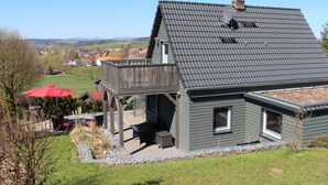 A modern house with a sloped roof, a balcony, and a patio area. - Holiday Home Naturally Good (Voehl)