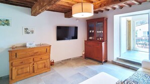 Een kamer met een houten kast, een televisie en een groot raam.