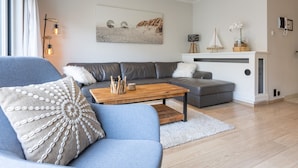 En moderne stue med en grå sofa, en blå lænestol og et træbord.