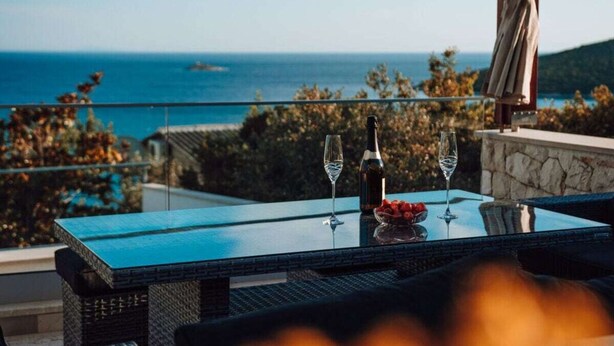 A table with two glasses and a bottle, overlooking a coastal view. - Brdar Comfortable Holiday Residence (Marina)