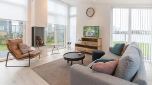 Una sala de estar moderna con un sofá, un sillón y una chimenea.