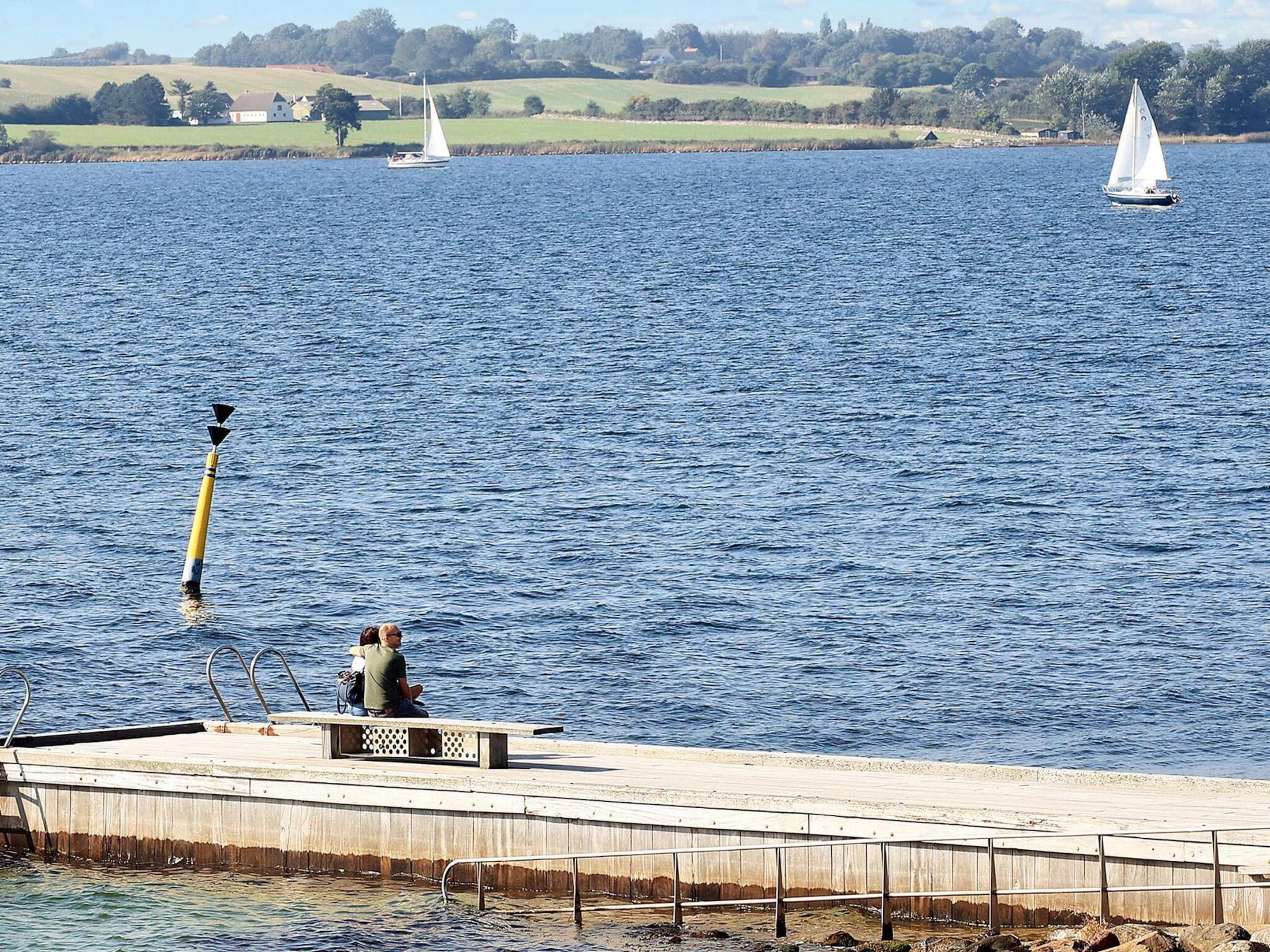 A pier with a concrete walkway, a metal railing, and a bench.