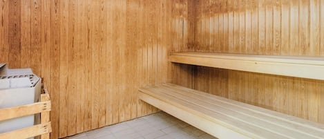 Un sauna con paredes de madera, un banco y piso de baldosas.