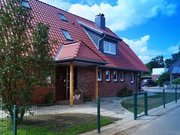Ein zweistöckiges Haus mit roten Ziegeln, einem Schornstein und einer kleinen Veranda.