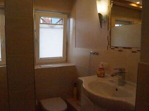 Ein kleines Badezimmer mit Toilette, Waschbecken und Fenster.