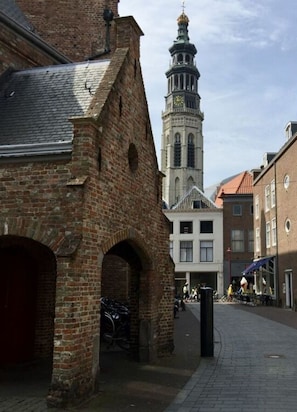 A historic brick building with a tower and arched doorway, located in a pedestrian area with other buildings and a bicycle. - Holiday Home in Kamperland Near Lake (Kamperland)