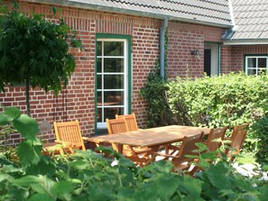 Sit and dine in the charming outdoor space surrounded by lush greenery and a beautifully maintained garden.