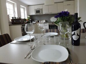 Enjoy a romantic dinner for two in this elegant dining area, complete with a beautifully set table and a vase of fresh flowers.